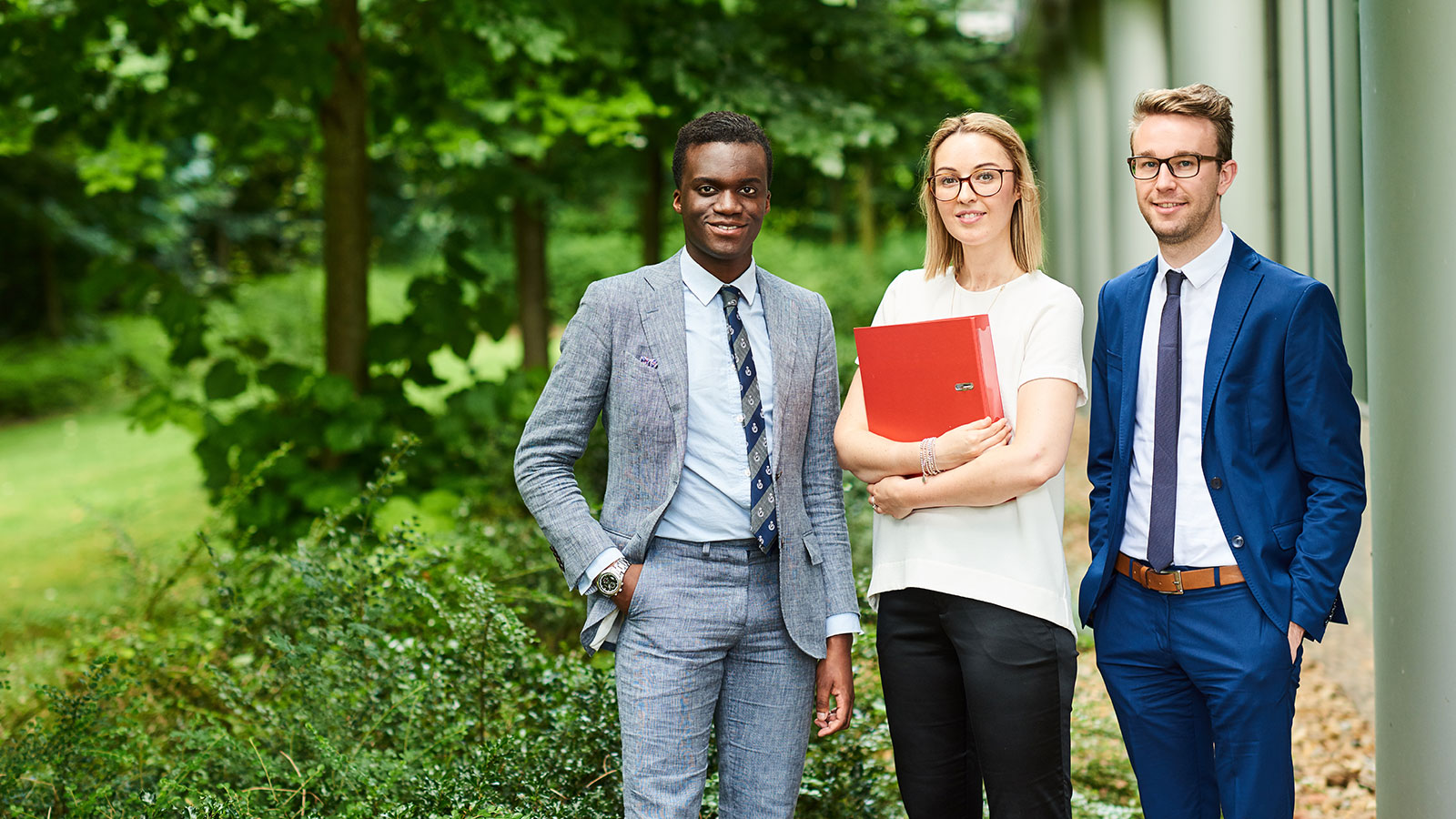 Young graduates standing in a garder holding brochures